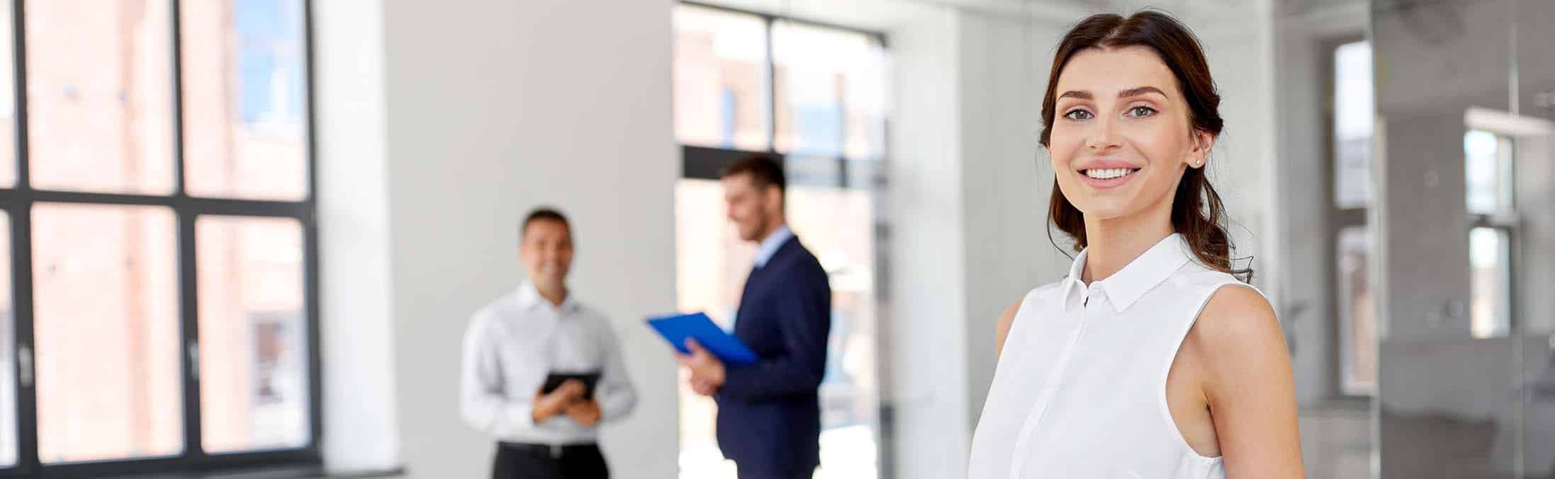 Portrait d'une femme heureuse agent immobilier. Deux hommes en fond
